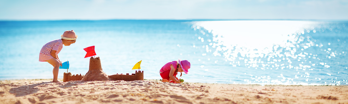 Lapset rakentavat hiekkalinnaa rannalla.